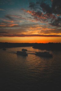 Silhouetted boats cruising on Moscow River at sunset, capturing a serene evening scene.