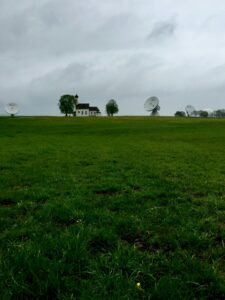 Scenic countryside view with satellite dishes and a lonely house on a cloudy day.